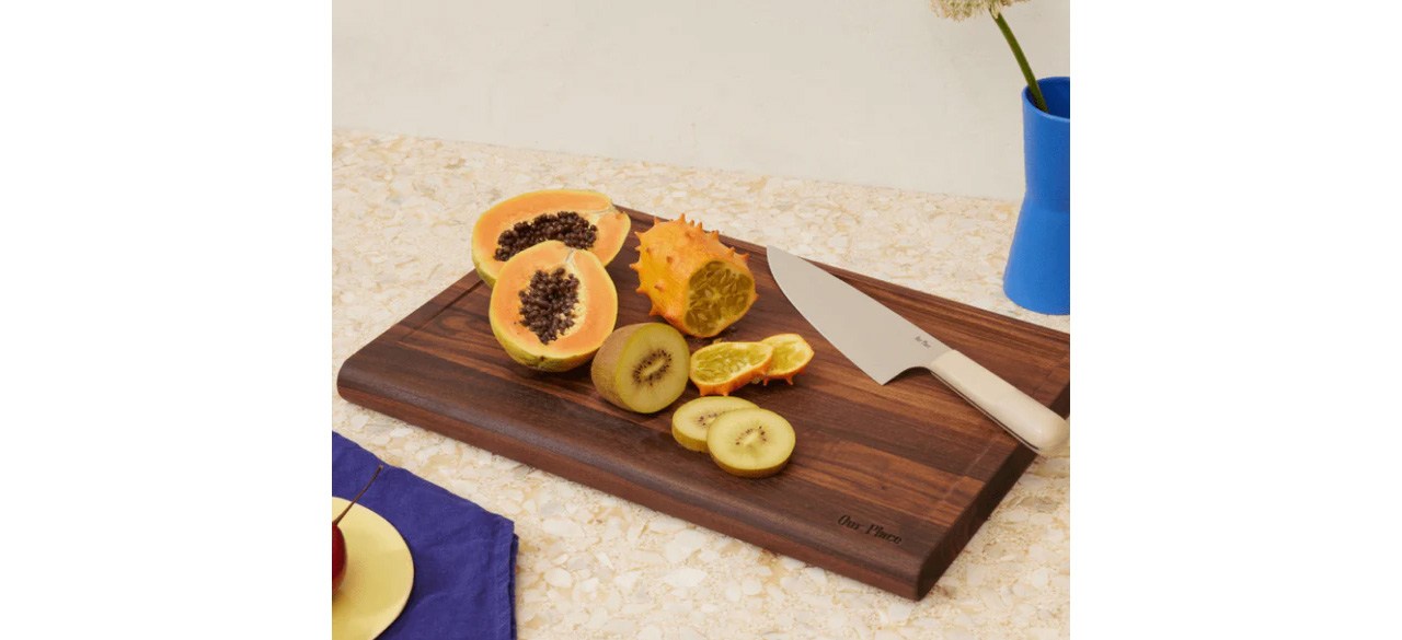 Our Place Walnut Cutting Board with knife and fruit on countertop