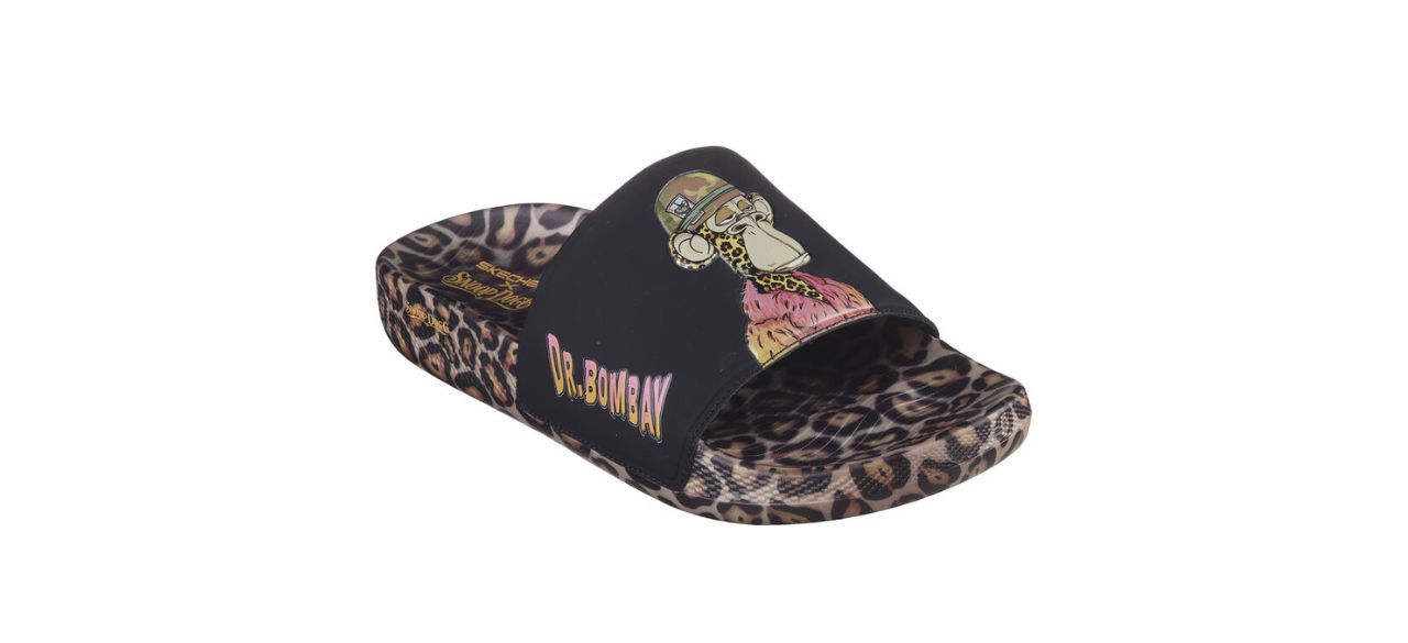 cheetah print slide sandals with a black upper portion that has a cartoon image of Dr. Bombay on the top and the words "Dr. Bombay" on the side.