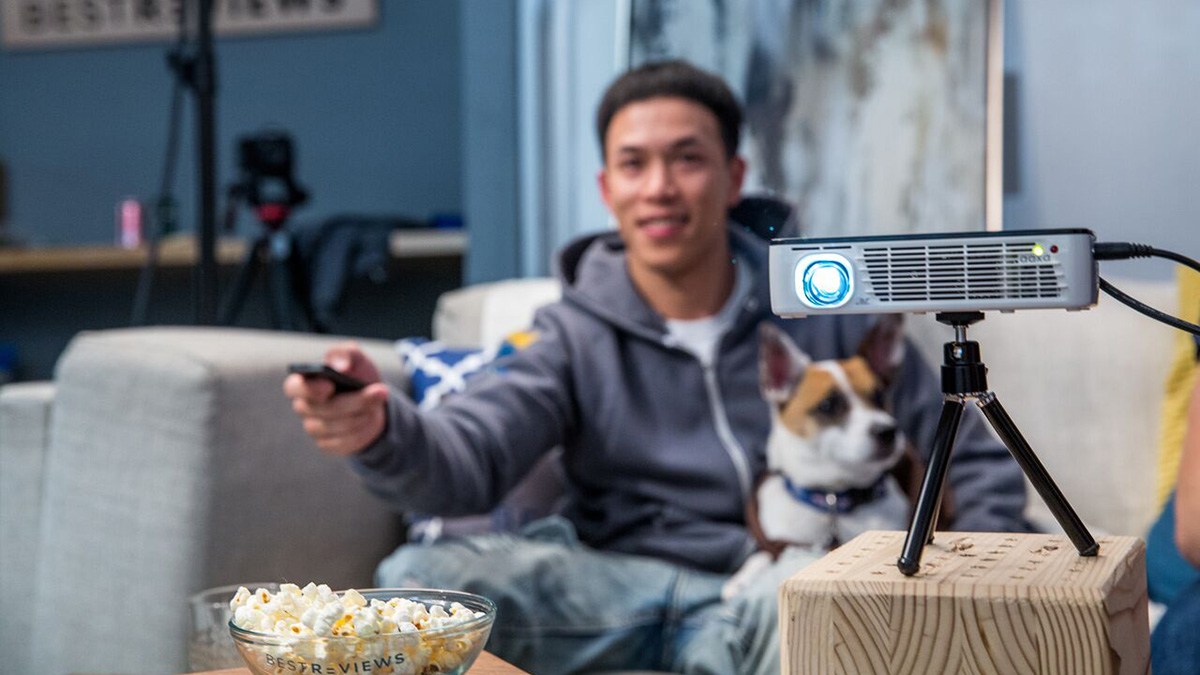 Person sitting on sofa using portable projector