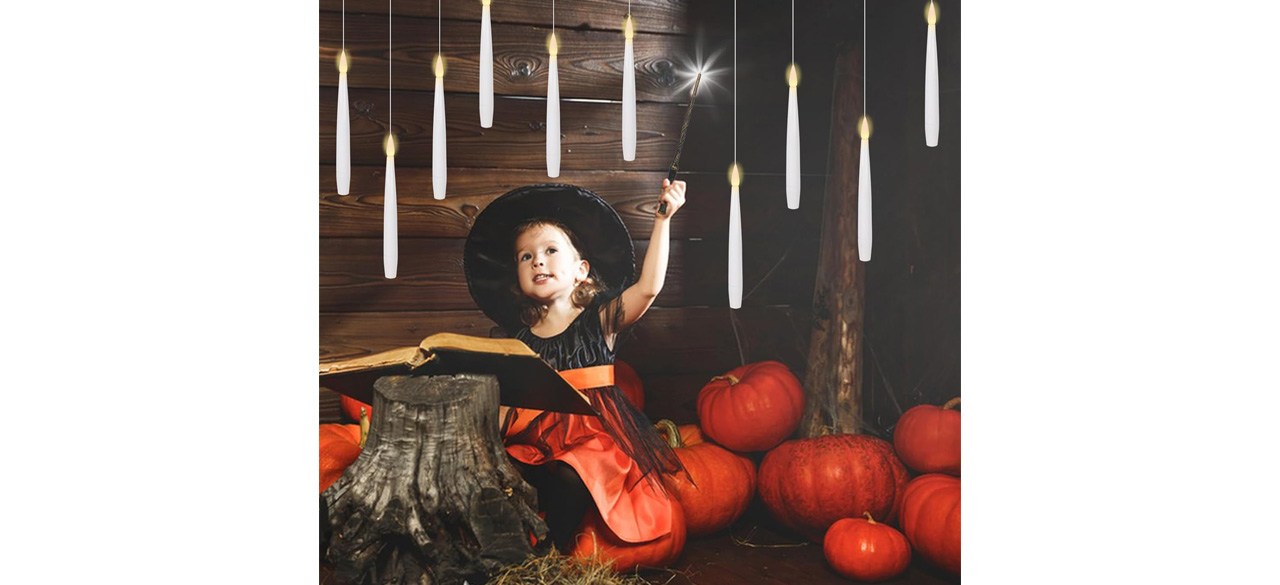 Child in costume with flameless floating candles and magic wand remote