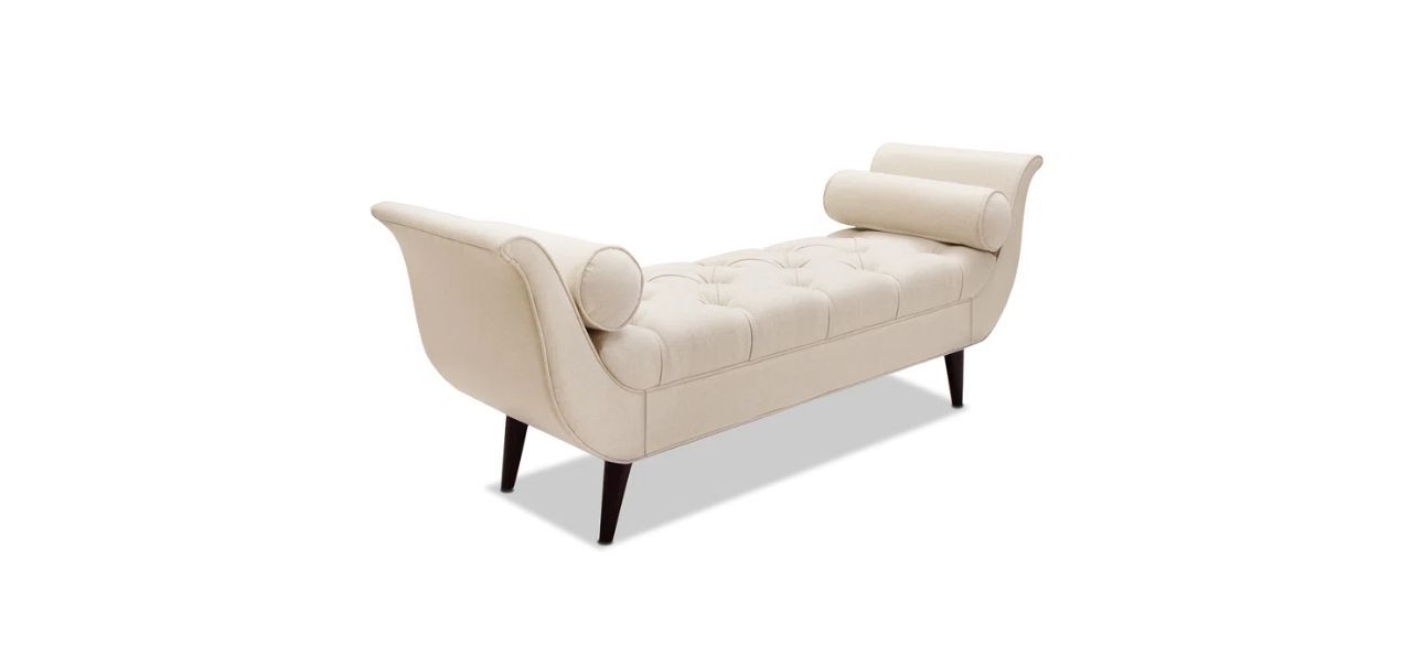 a tufted, white mid-century modern bench with two cylindrical pillows