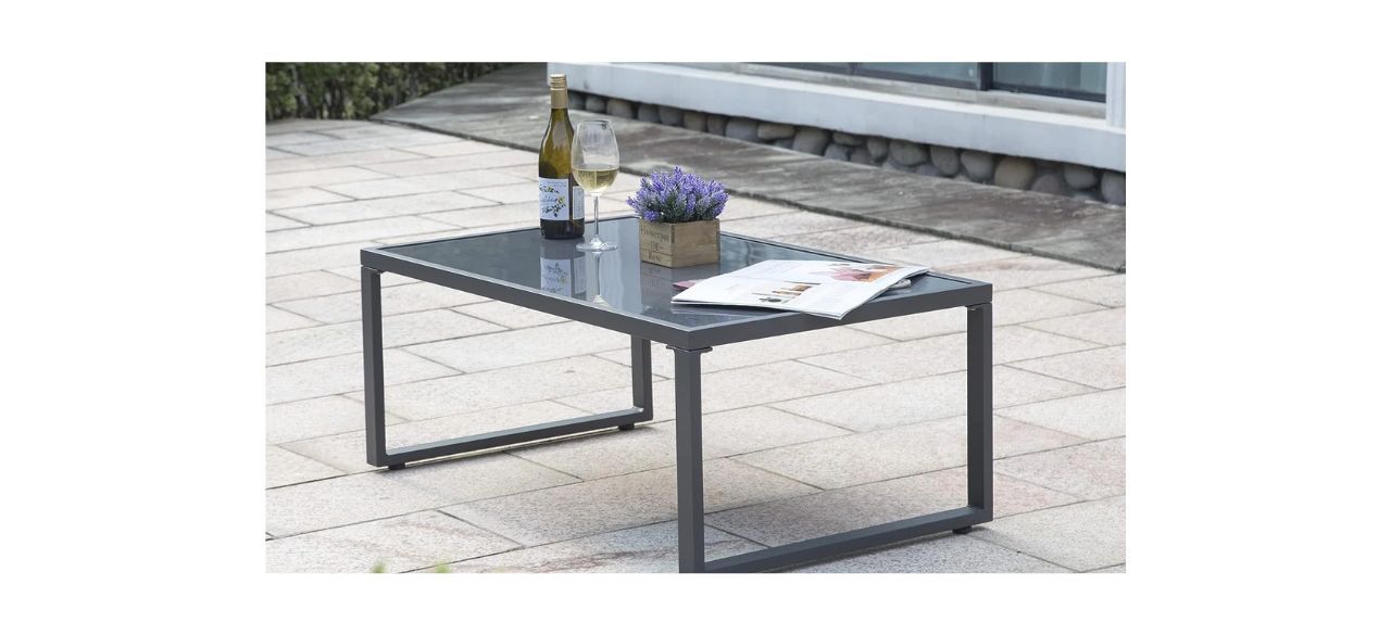 Ivy Bronx Rectangular Outdoor Coffee Table on a patio with stuff on it