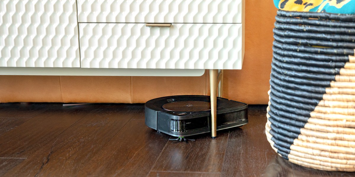 Roomba cleaning hardwood floor as it navigates around furniture