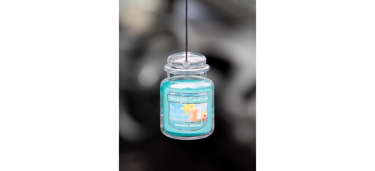 Blue Yankee Candle Car Air Freshener hanging from car rearview mirror out of frame