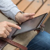 Person using iPad on park bench