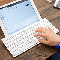 Person typing on keyboard connected to iPad